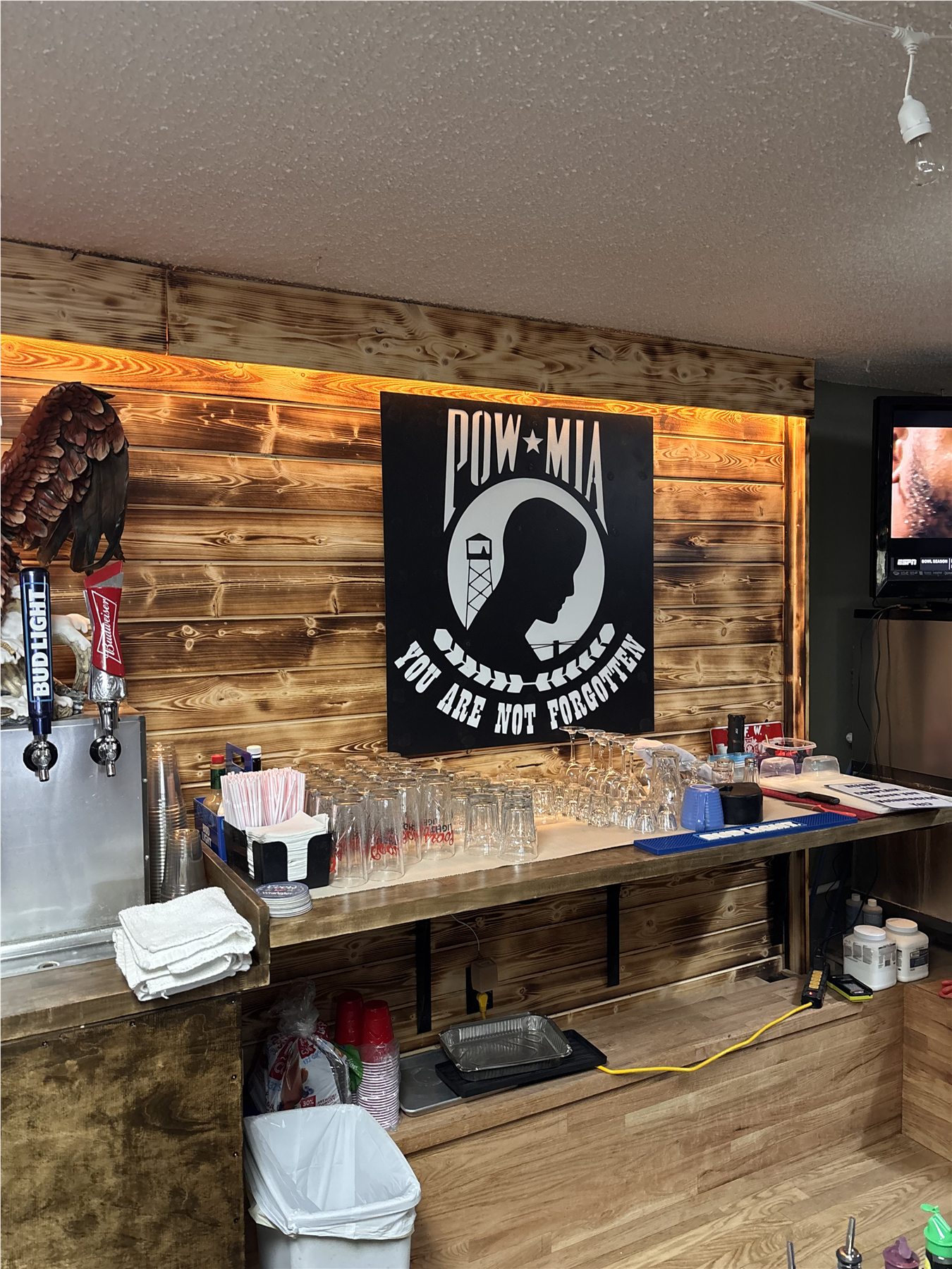 Custom black and white POW-MIA metal wall sign installed behind a bar